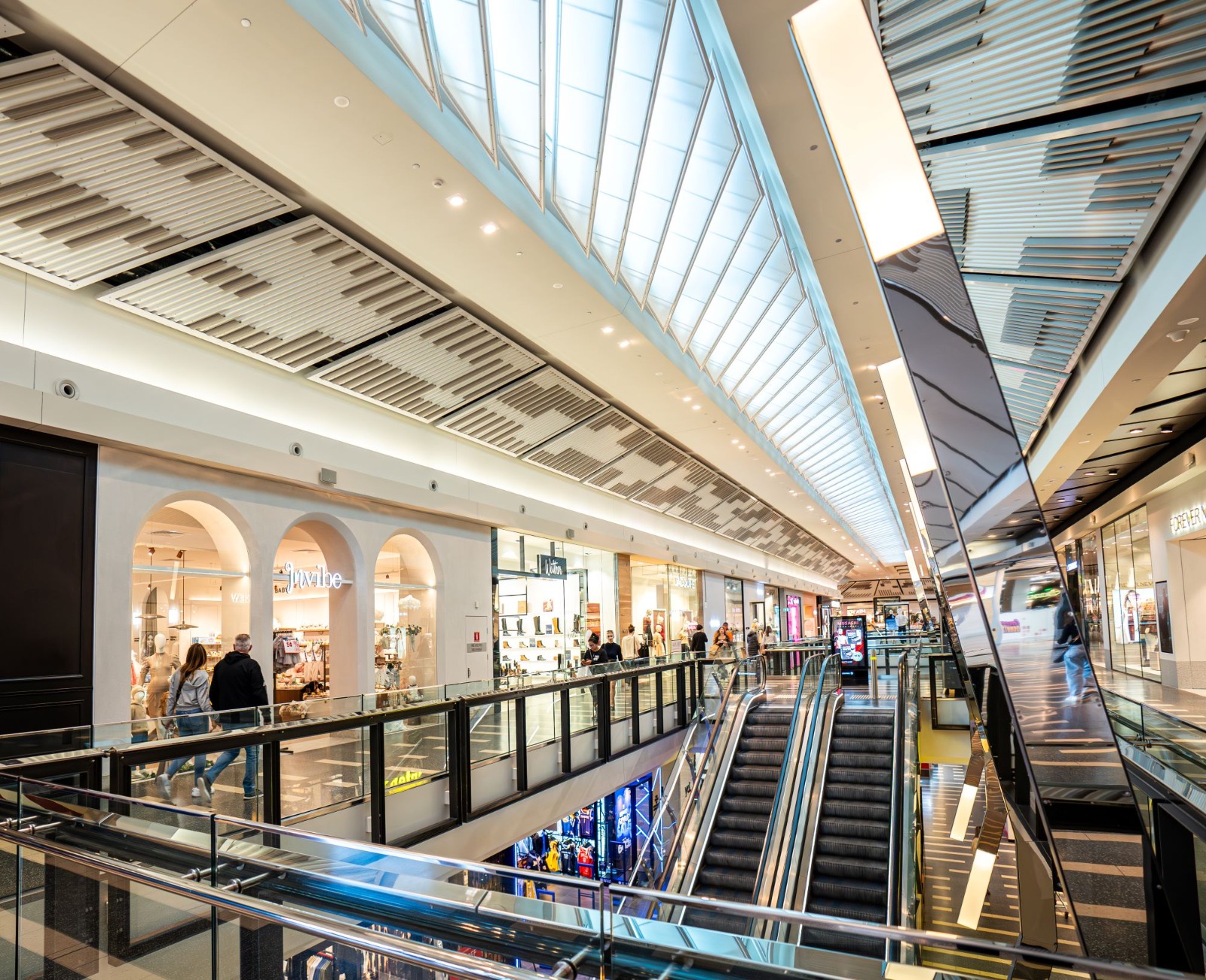 A premium centre atrium: diamond skylight, escalator vault, marble floor.